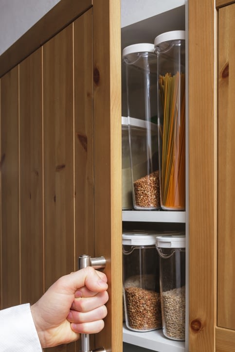 a person opening a pantry cupboard door