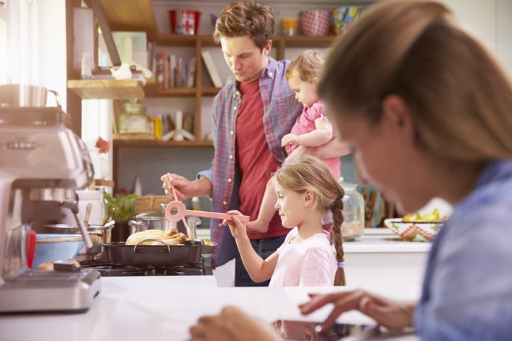 a mom works on the busy family schedule with her family in the background